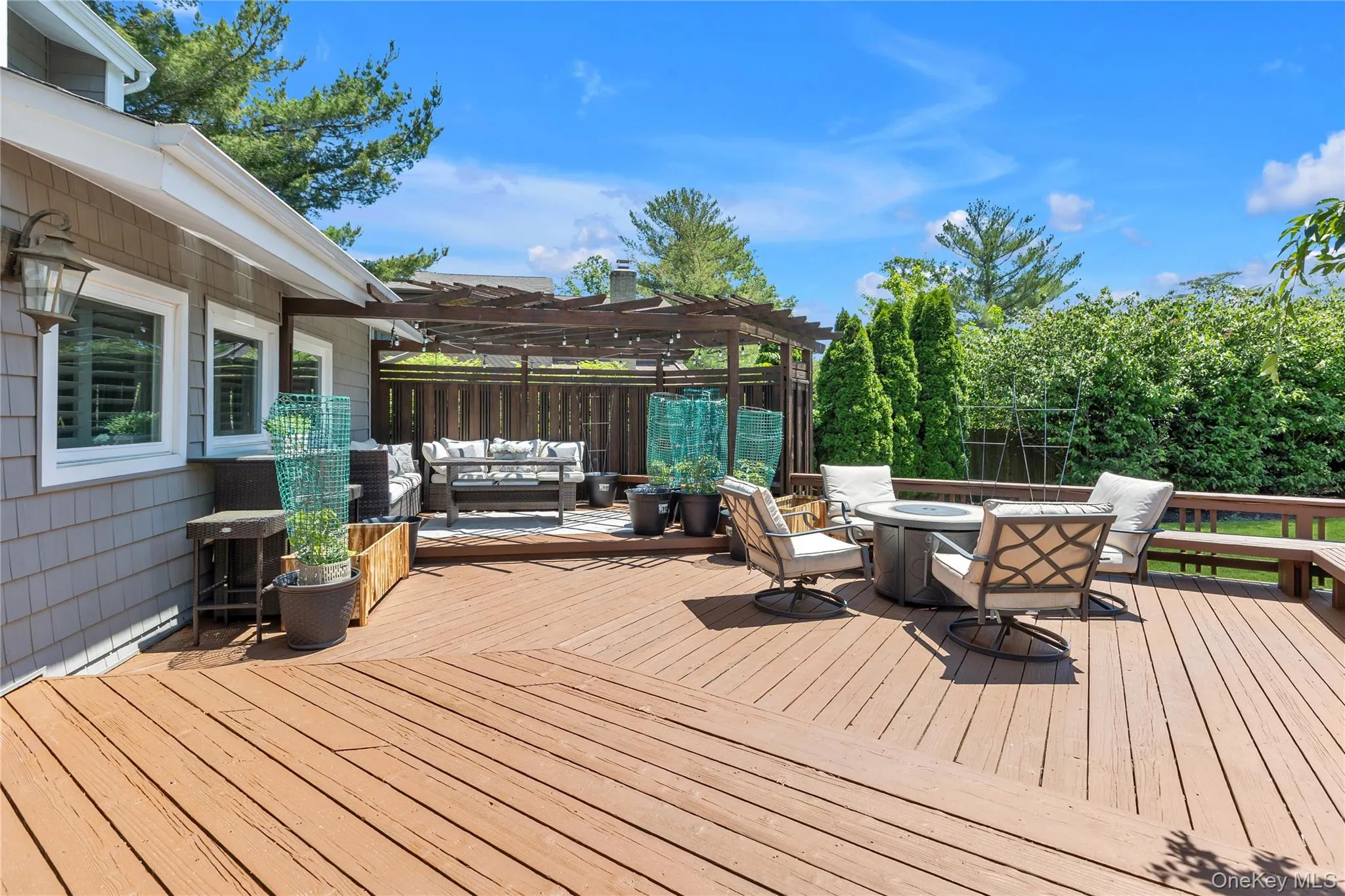 Expansive outdoor deck featuring wood-finish decking, a built-in pergola, and a private perimeter of mature trees Expansive outdoor deck featuring wood-finish decking, a built-in pergola, and a private perimeter of mature trees