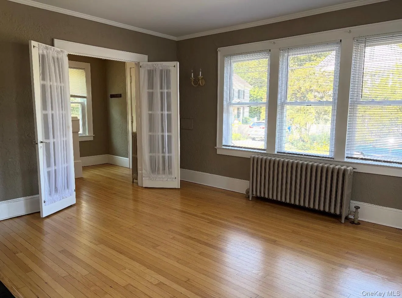 Wood-finish flooring, white trim, multiple windows with blinds, and French doors Wood-finish flooring, white trim, multiple windows with blinds, and French doors