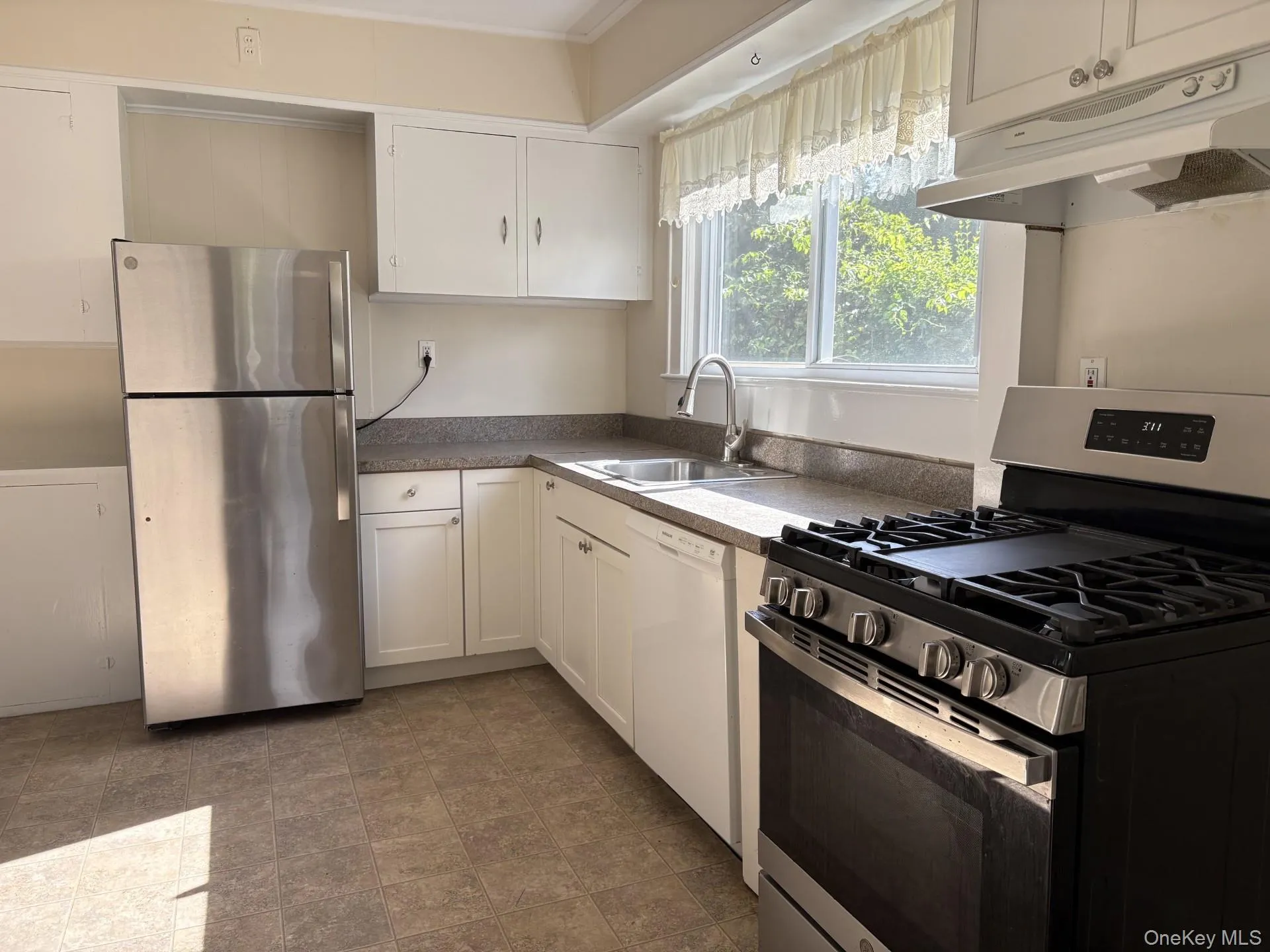 Kitchen featuring gas cooking, white cabinetry, a double basin sink, and wood-finish flooring Kitchen featuring gas cooking, white cabinetry, a double basin sink, and wood-finish flooring