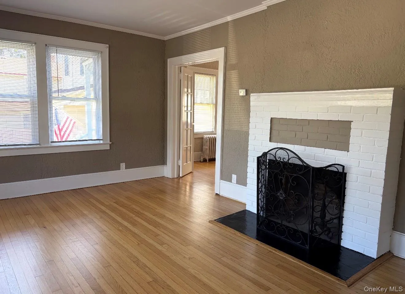 Hardwood flooring, painted brick fireplace with hearth, white window trim, cased opening, and glass-paneled double doors Hardwood flooring, painted brick fireplace with hearth, white window trim, cased opening, and glass-paneled double doors