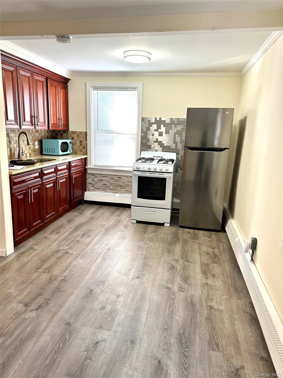 Kitchen featuring sink, crown molding, light hardwood / wood-style flooring, stainless steel refrigerator, and white range with gas cooktop Kitchen featuring sink, crown molding, light hardwood / wood-style flooring, stainless steel refrigerator, and white range with gas cooktop