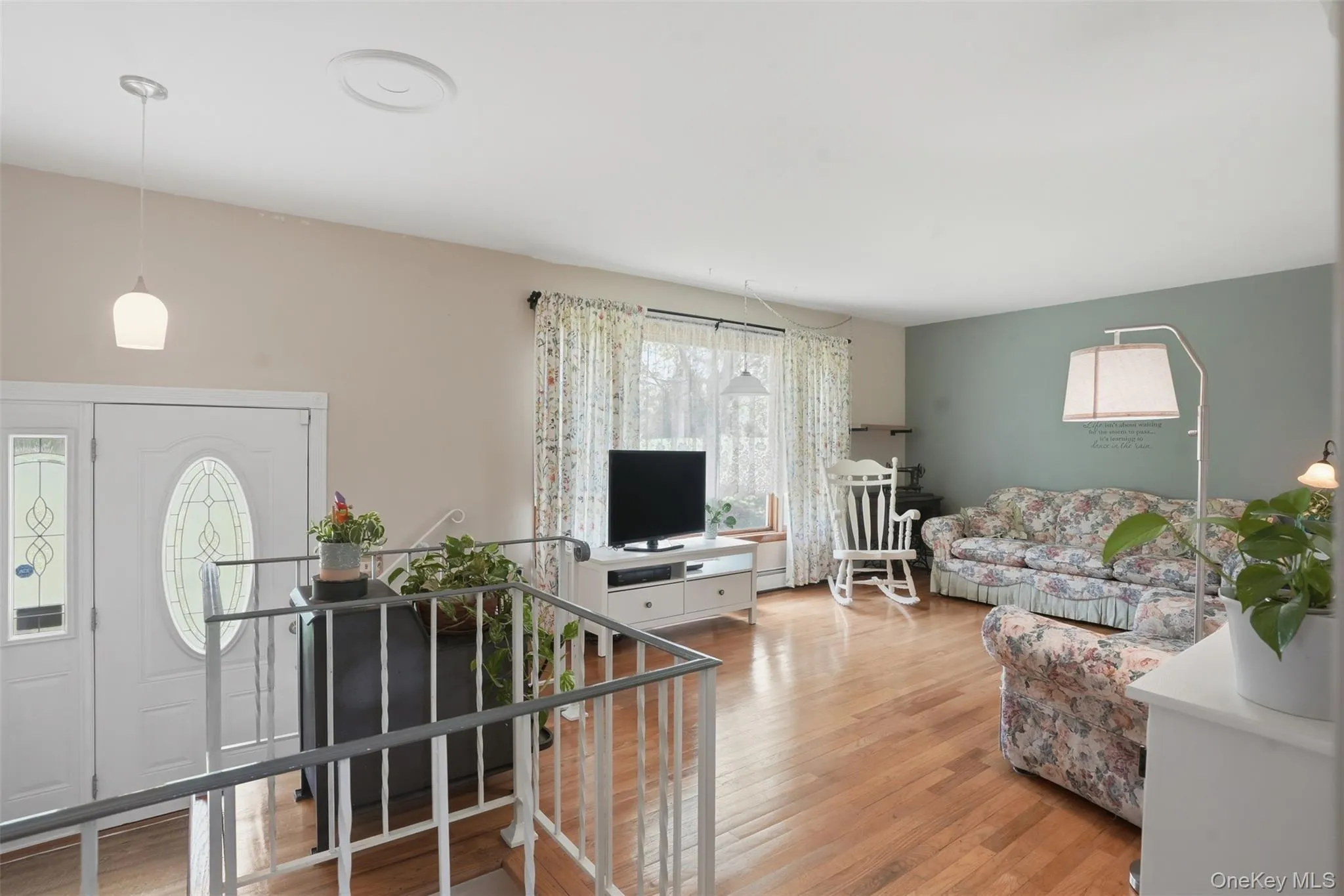 Upon entering, a short stairway leads you to this bright and spacious living room with wood floors and large window Upon entering, a short stairway leads you to this bright and spacious living room with wood floors and large window