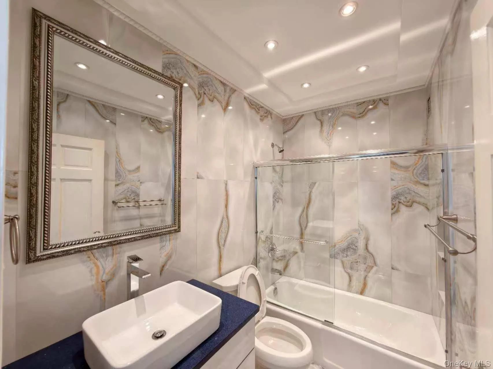 Bathroom featuring tile walls, combined bath / shower with glass door, recessed lighting, and vanity Bathroom featuring tile walls, combined bath / shower with glass door, recessed lighting, and vanity