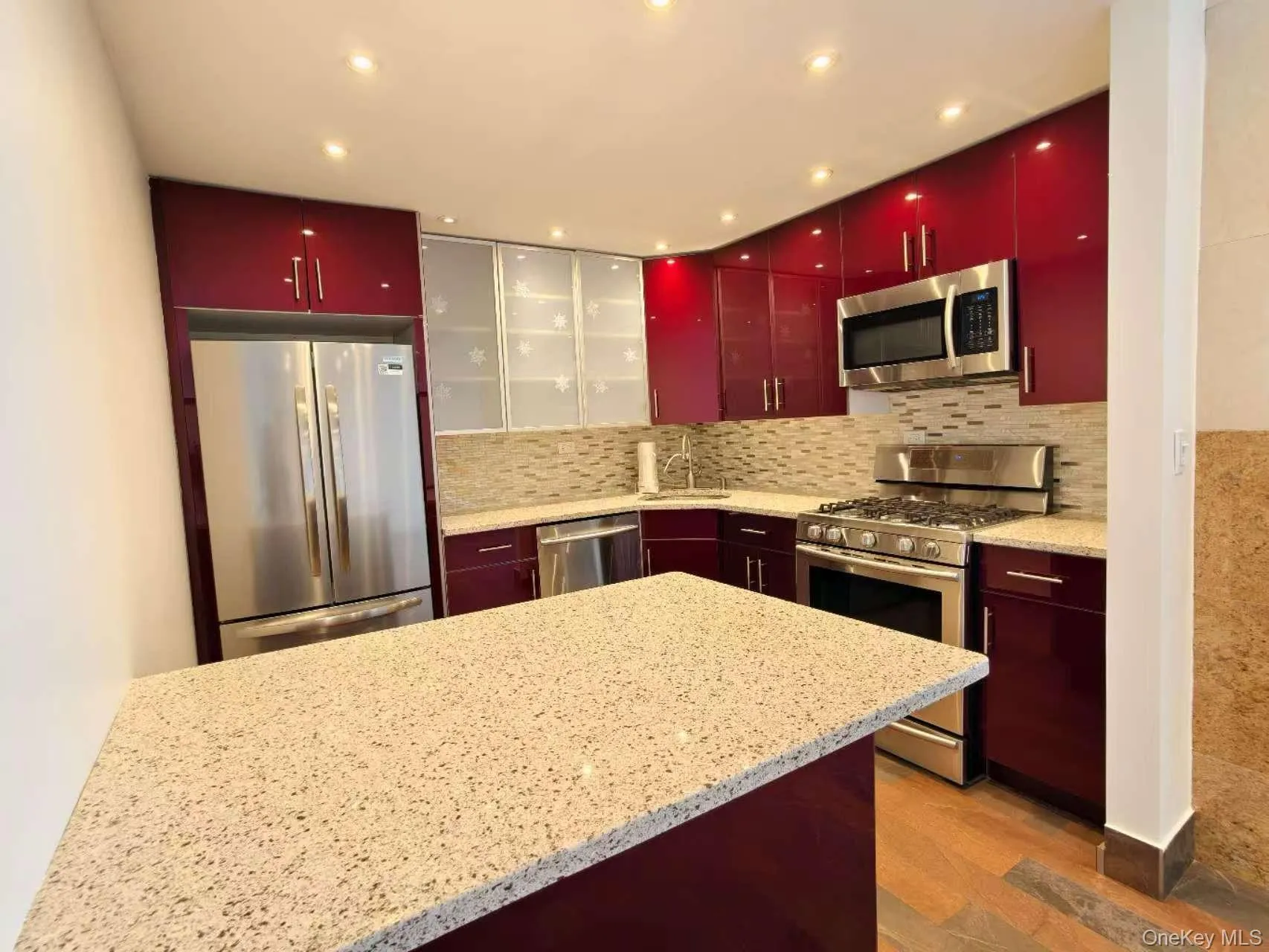 Kitchen with appliances with stainless steel finishes, red cabinetry, tasteful backsplash, and recessed lighting Kitchen with appliances with stainless steel finishes, red cabinetry, tasteful backsplash, and recessed lighting
