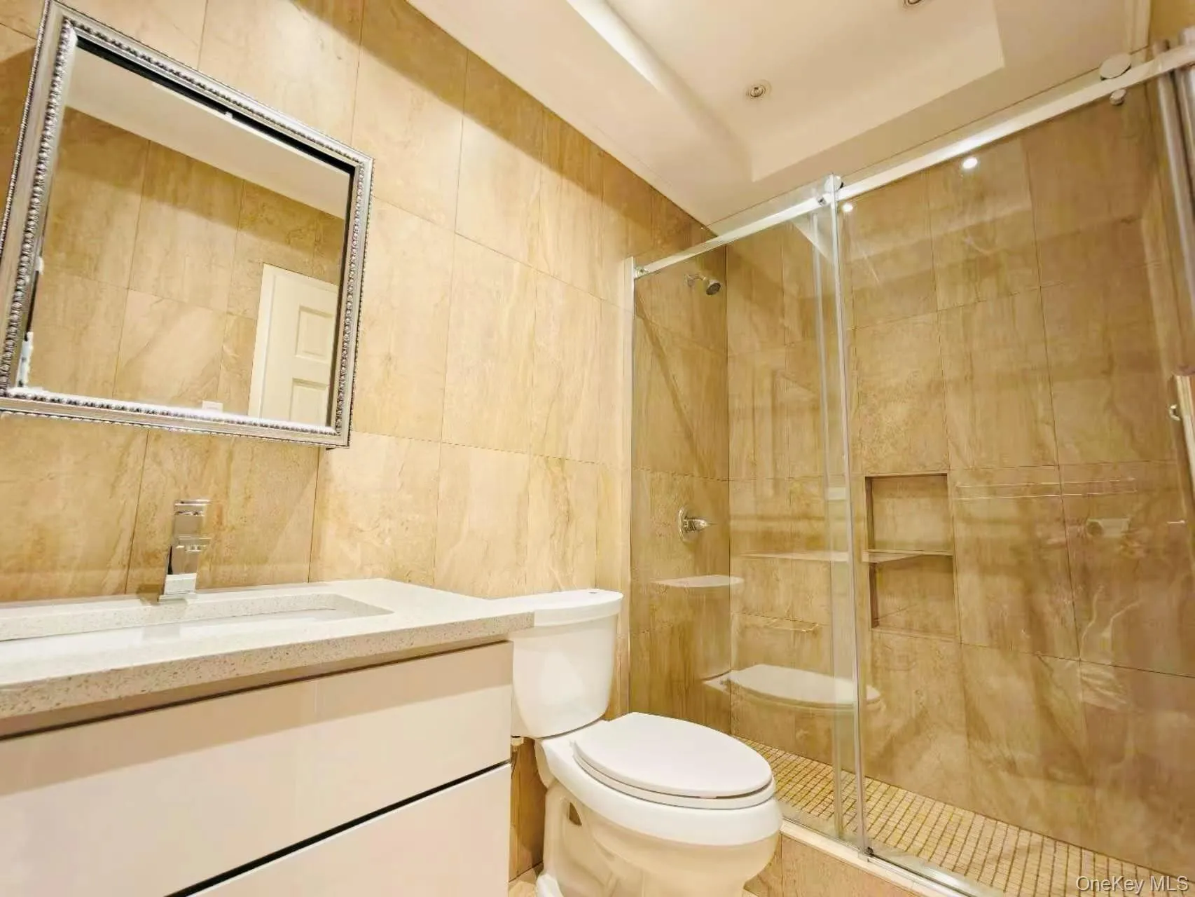 Bathroom with tile walls, vanity, and a shower stall Bathroom with tile walls, vanity, and a shower stall