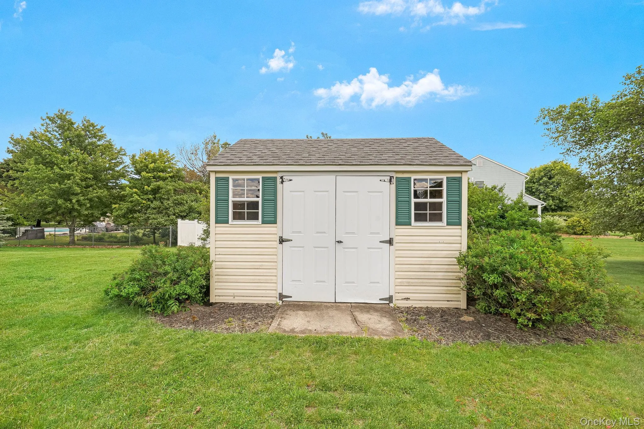 Storage shed with dual entry doors and two windows featuring decorative green shutters. Storage shed with dual entry doors and two windows featuring decorative green shutters.