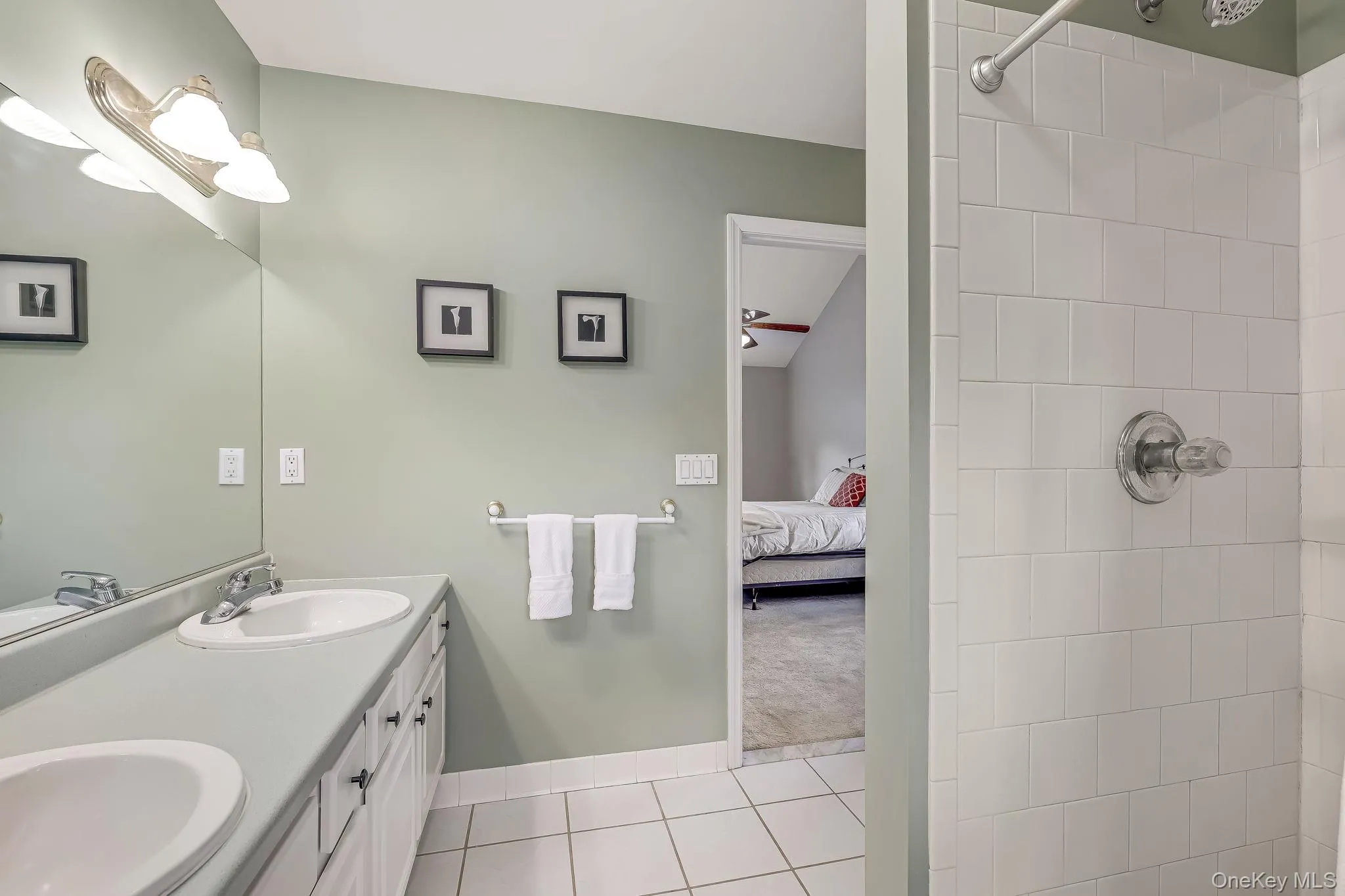 Featuring a double vanity with white cabinetry and light-toned countertops. Featuring a double vanity with white cabinetry and light-toned countertops.