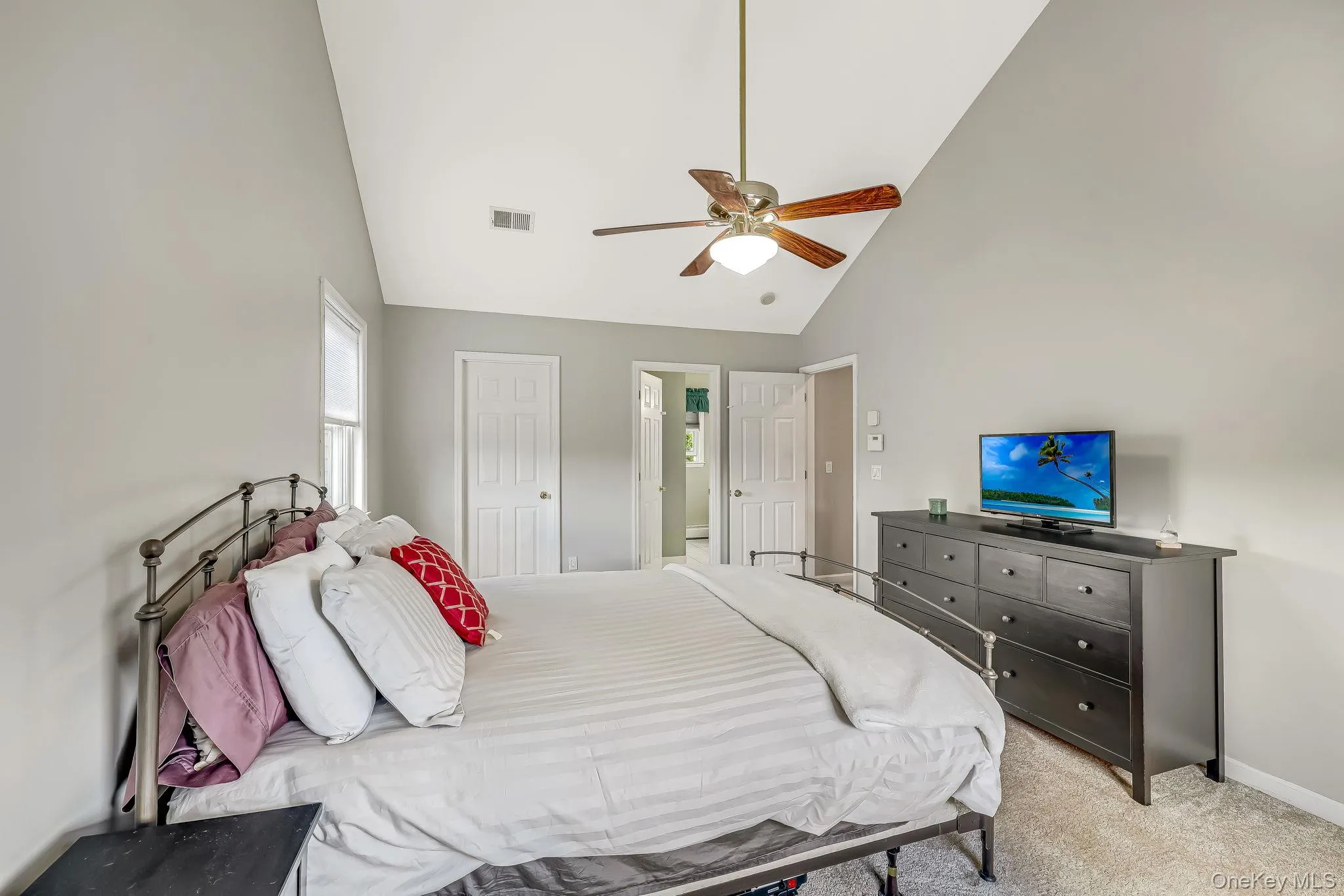 Vaulted ceiling in the primary bedroom featuring a ceiling fan with integrated lighting, neutral wall tones, and carpet flooring Vaulted ceiling in the primary bedroom featuring a ceiling fan with integrated lighting, neutral wall tones, and carpet flooring