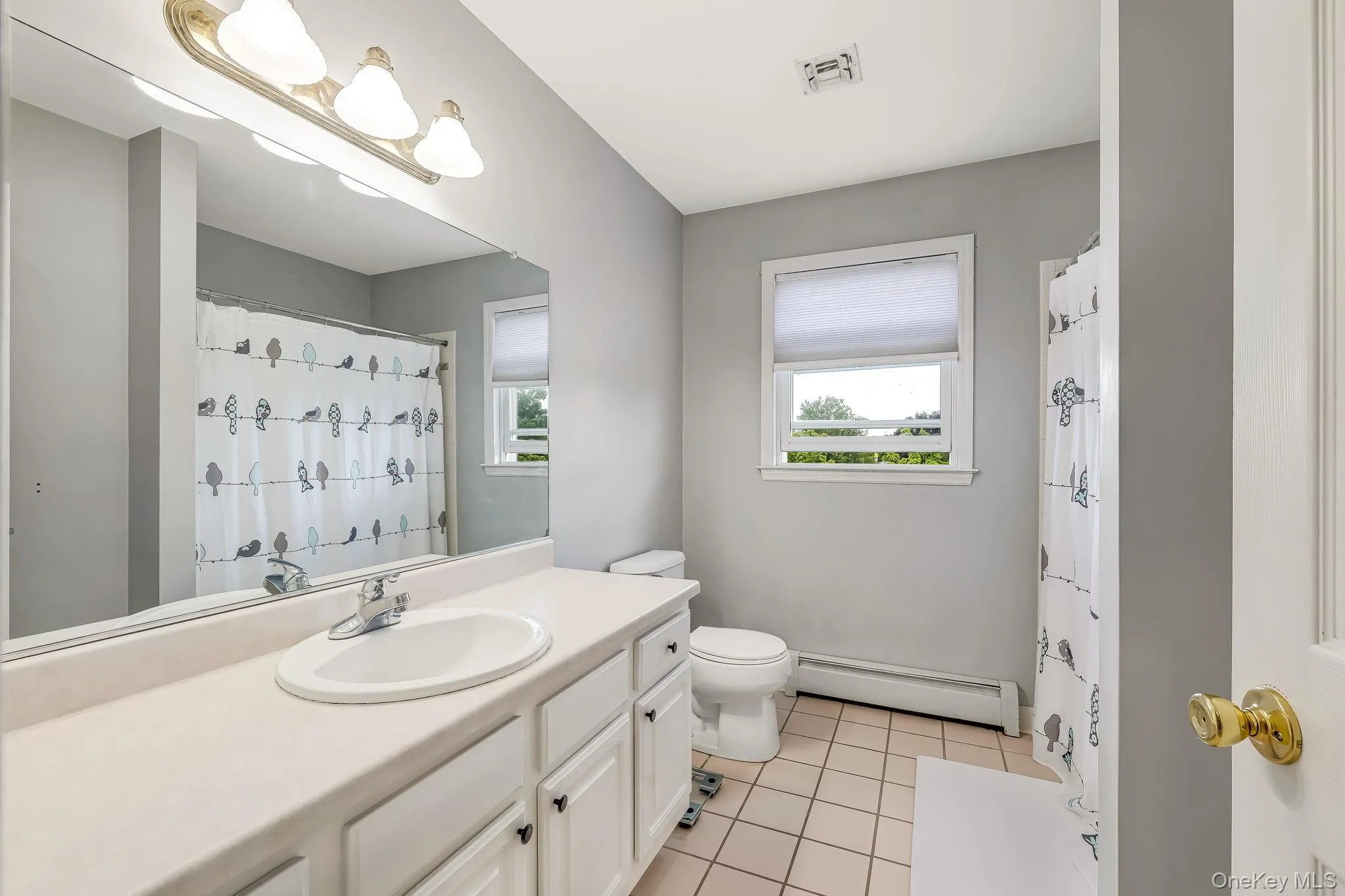 The second full bathroom has a vanity with an integrated sink, broad mirror, and overhead tri-bulb lighting The second full bathroom has a vanity with an integrated sink, broad mirror, and overhead tri-bulb lighting