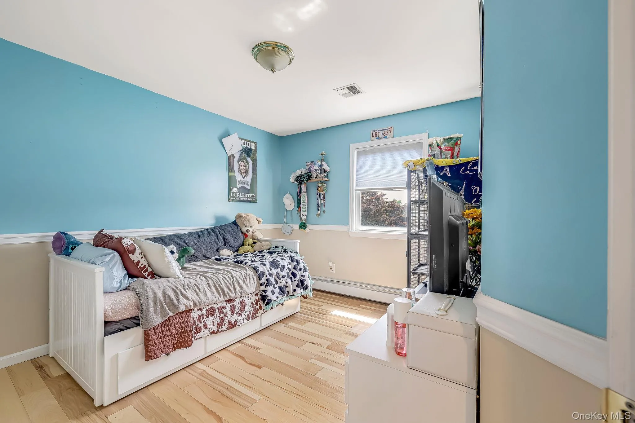 Room featuring wood-finish flooring, chair rail molding, a single window, and a flush-mount ceiling light. Room featuring wood-finish flooring, chair rail molding, a single window, and a flush-mount ceiling light.