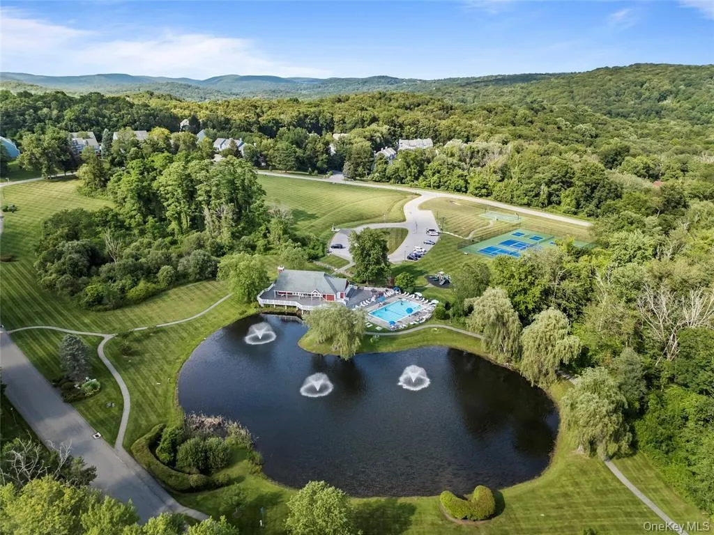 Expansive aerial view showcasing Fieldstone pond with three fountains, surrounded by manicured lawns and mature trees Expansive aerial view showcasing Fieldstone pond with three fountains, surrounded by manicured lawns and mature trees