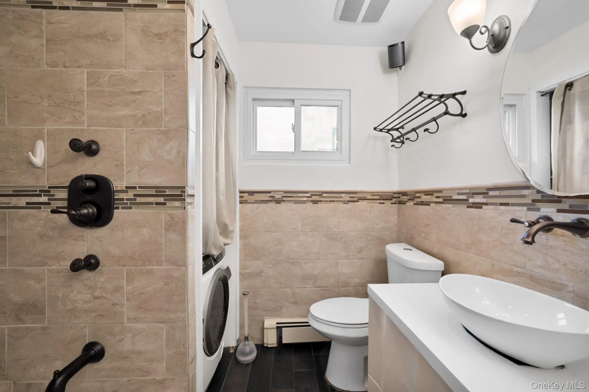Bathroom featuring a vessel sink on a white countertop, dark wood-finish flooring, tiled shower with bronze fixtures, and a glass-block privacy window Bathroom featuring a vessel sink on a white countertop, dark wood-finish flooring, tiled shower with bronze fixtures, and a glass-block privacy window