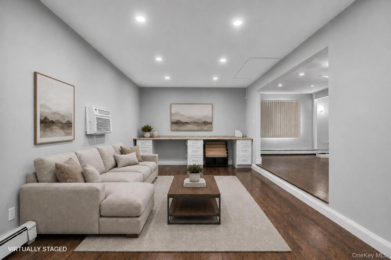 Open-concept living space featuring recessed lighting, wood-finish flooring, and a built-in desk with cabinetry Open-concept living space featuring recessed lighting, wood-finish flooring, and a built-in desk with cabinetry