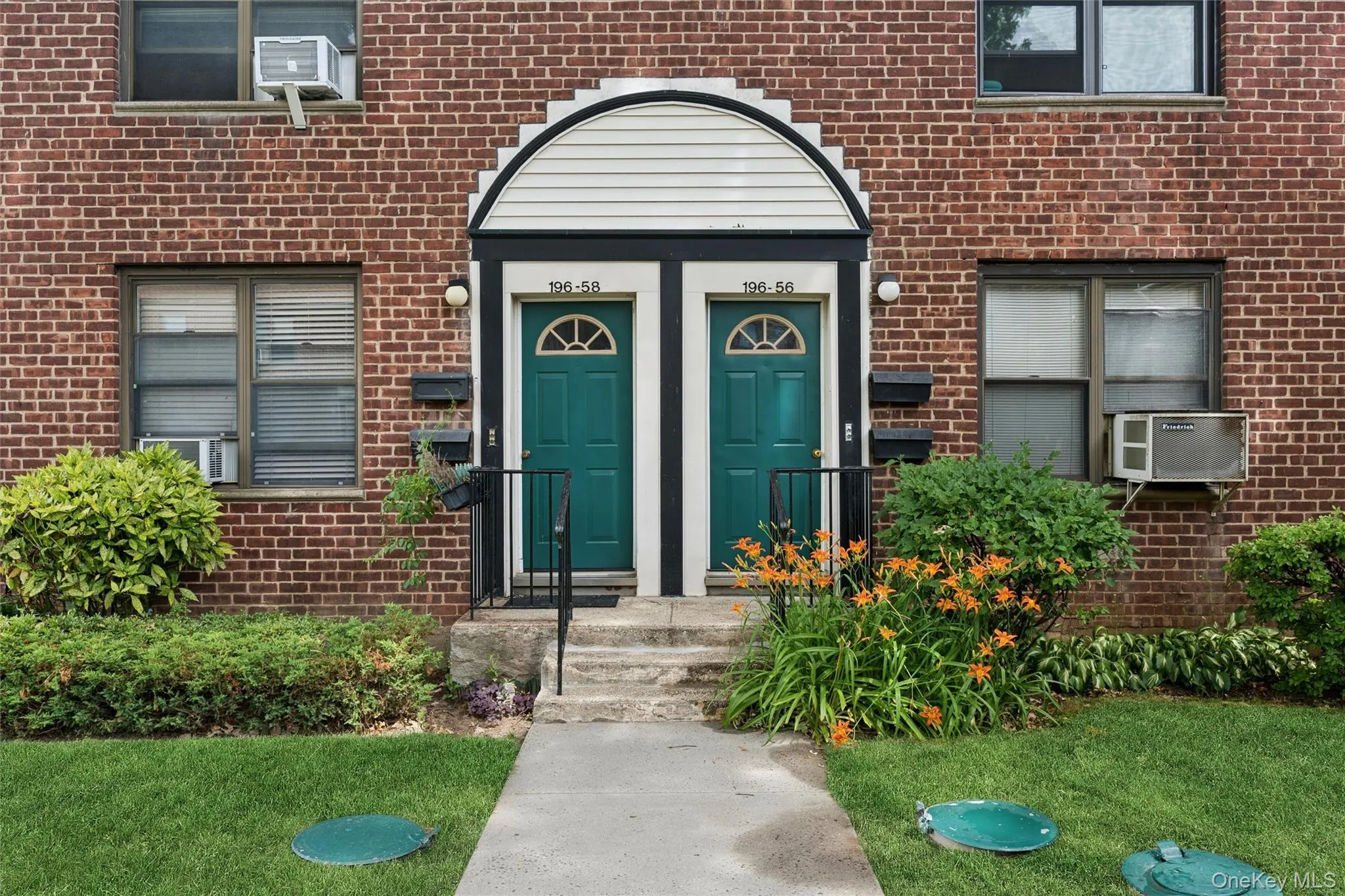 Brick facade building with a symmetrical entrance featuring arched white siding details Brick facade building with a symmetrical entrance featuring arched white siding details