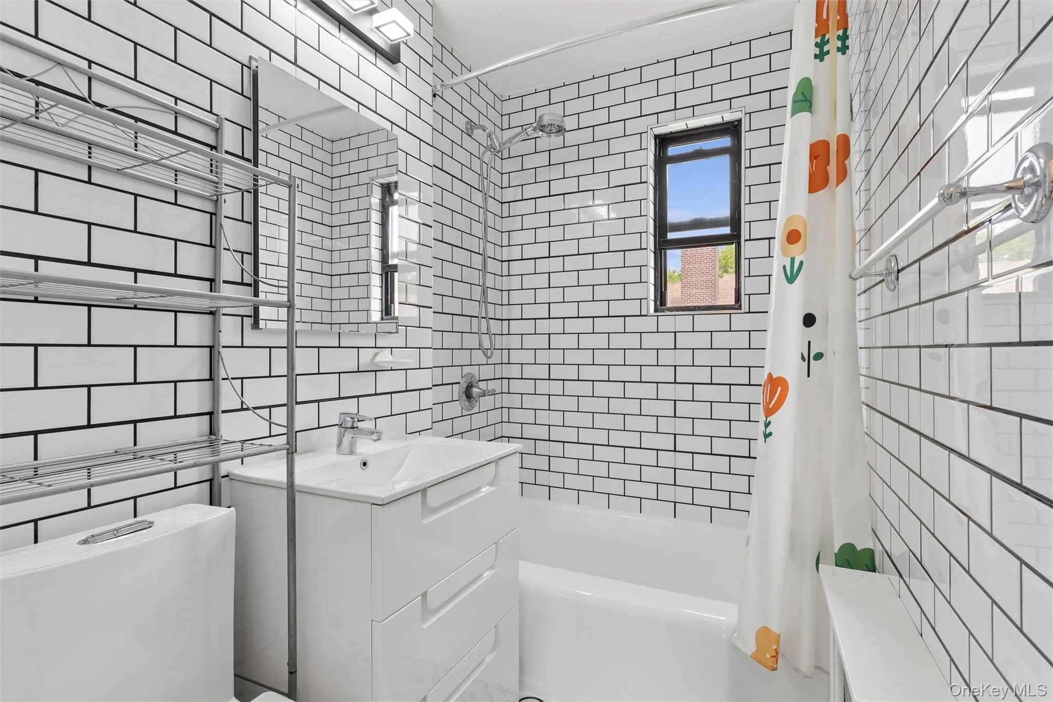 Bathroom featuring white subway tile with dark grout, a white vanity with integrated sink, chrome faucet, and a built-in bathtub with shower Bathroom featuring white subway tile with dark grout, a white vanity with integrated sink, chrome faucet, and a built-in bathtub with shower