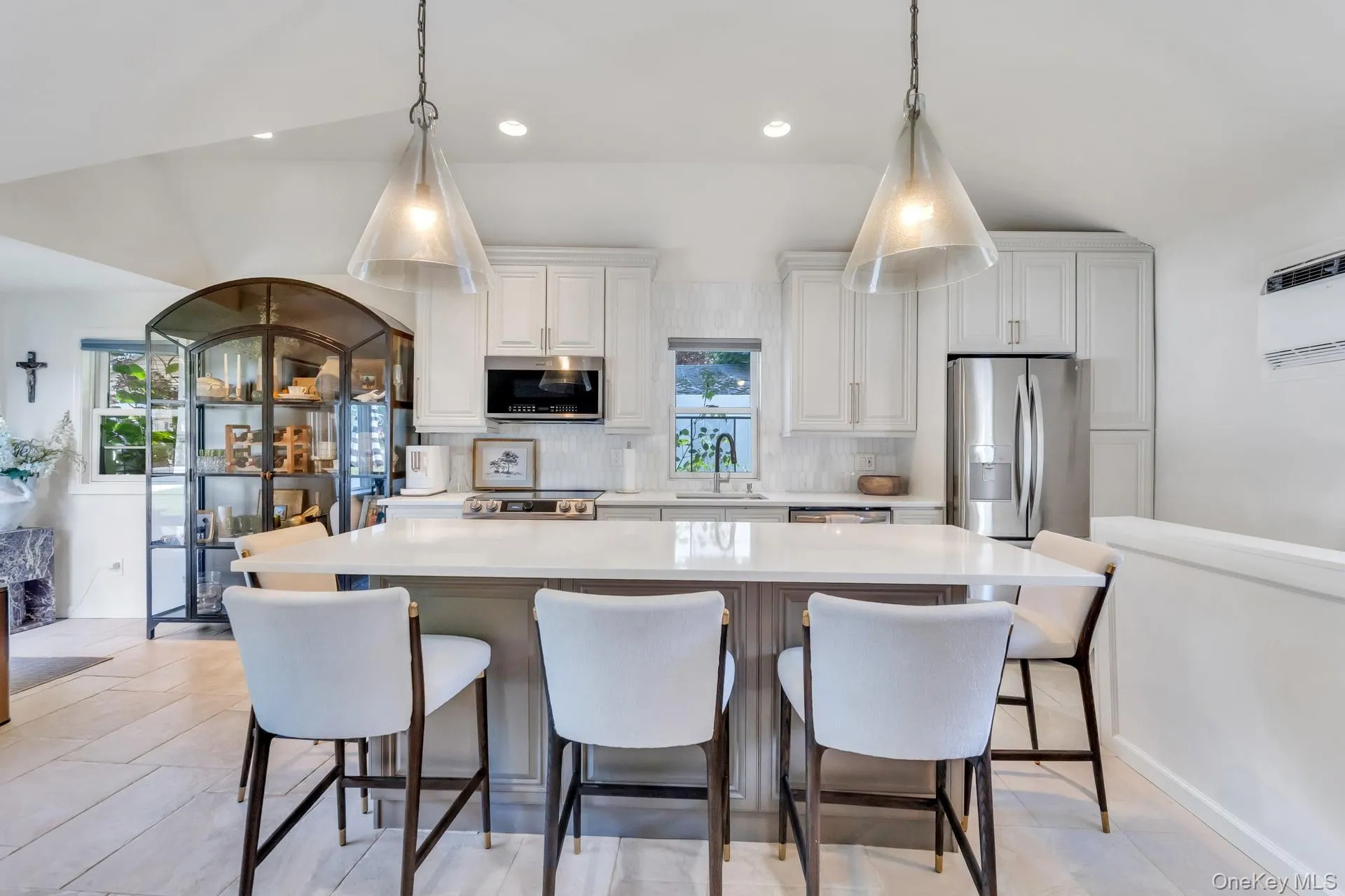 Modern kitchen featuring a central island with countertop seating, stainless steel appliances, white cabinetry, and wood-finish flooring Modern kitchen featuring a central island with countertop seating, stainless steel appliances, white cabinetry, and wood-finish flooring