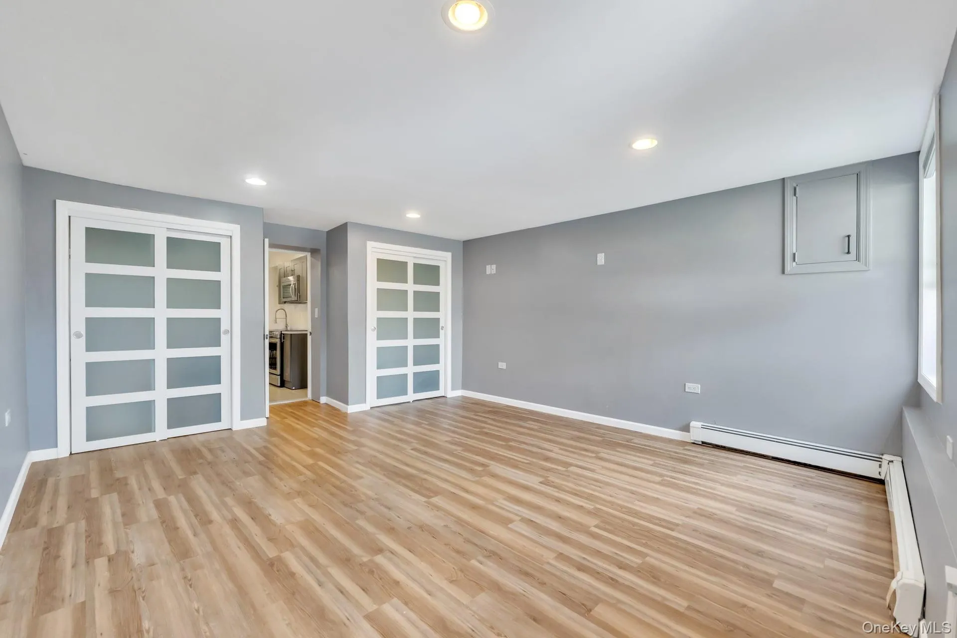 Spacious interior featuring wood-finish flooring, recessed lighting, and gray wall paint Spacious interior featuring wood-finish flooring, recessed lighting, and gray wall paint