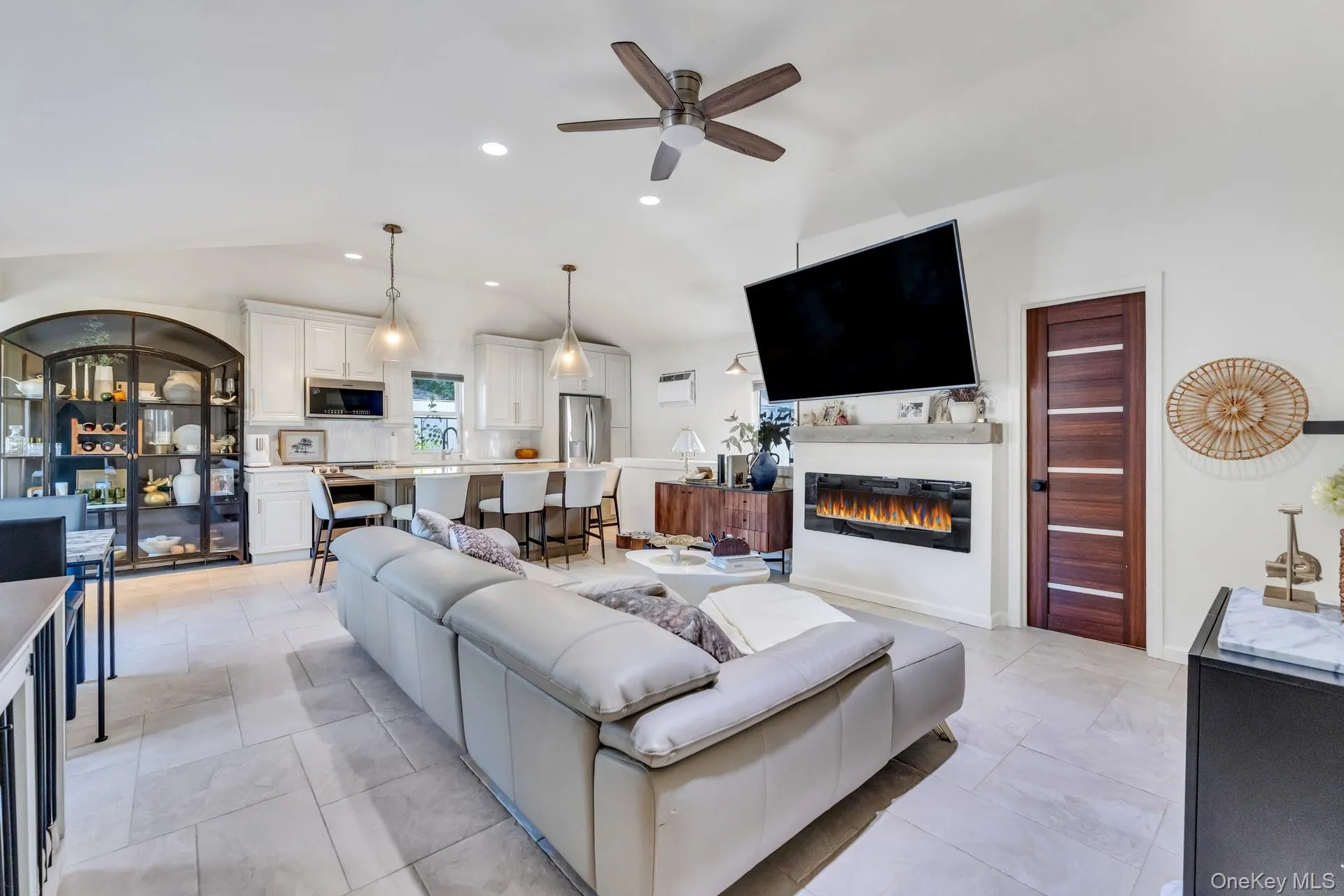 Spacious open-concept living area featuring a vaulted ceiling and light tile flooring Spacious open-concept living area featuring a vaulted ceiling and light tile flooring
