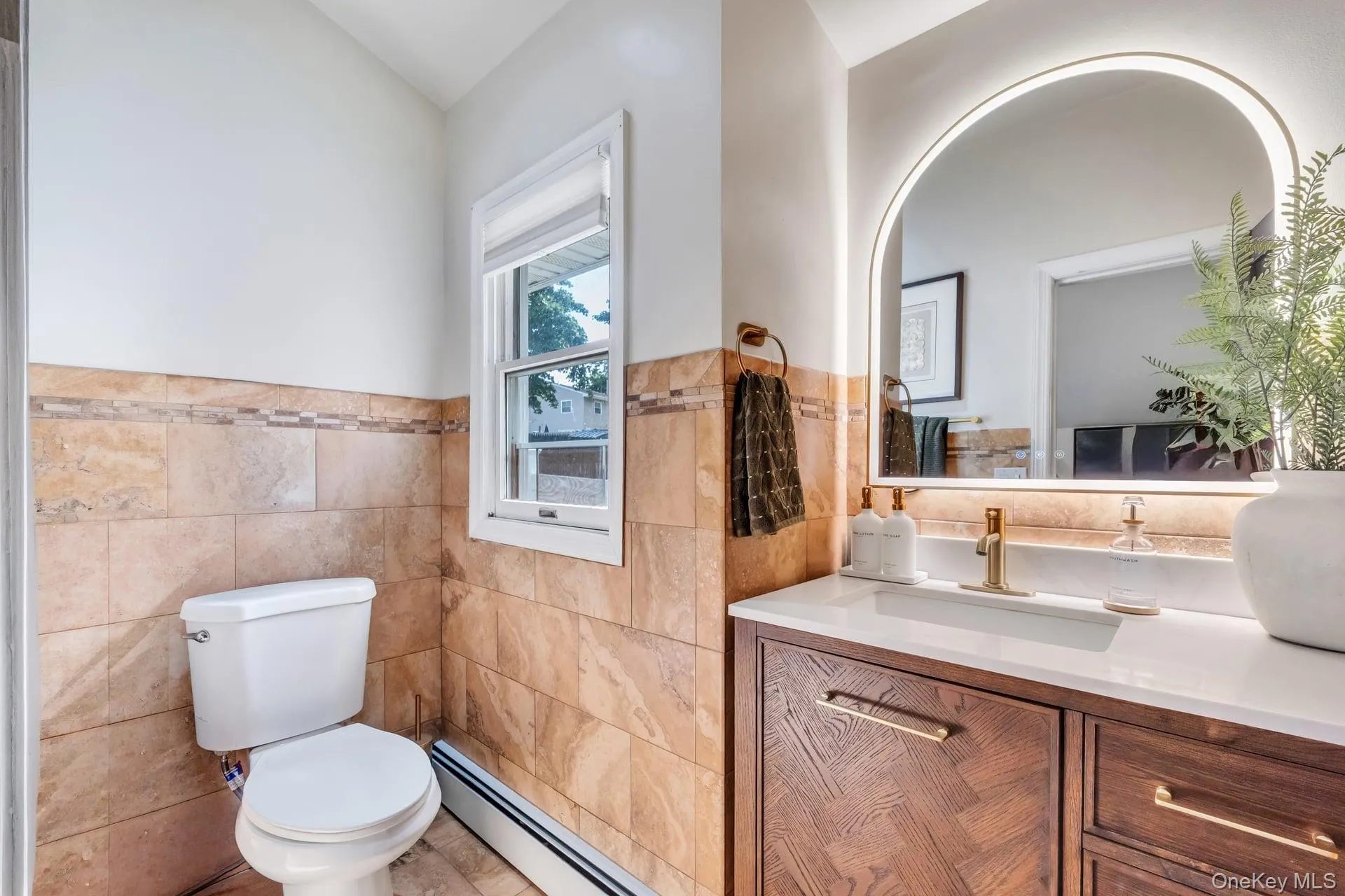 Bathroom vanity featuring a light quartz countertop, undermount sink, and a gold-toned faucet Bathroom vanity featuring a light quartz countertop, undermount sink, and a gold-toned faucet