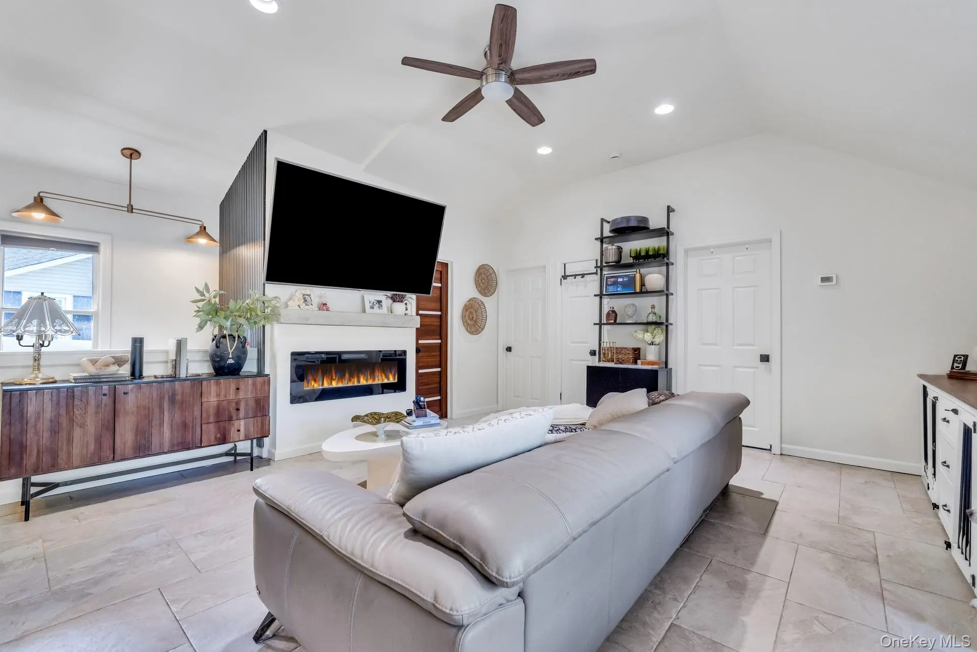 Vaulted ceiling living space with a modern linear fireplace, recessed lighting, and a ceiling fan Vaulted ceiling living space with a modern linear fireplace, recessed lighting, and a ceiling fan
