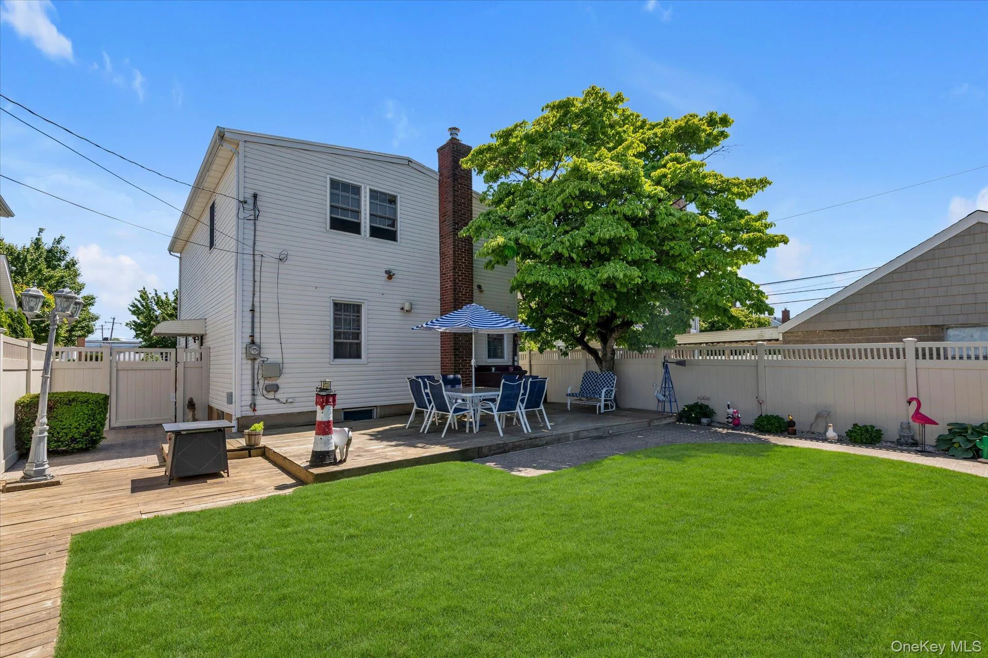 Expansive backyard featuring a lush lawn, a mature tree, and a spacious wood-finish deck for BBQ's Expansive backyard featuring a lush lawn, a mature tree, and a spacious wood-finish deck for BBQ's