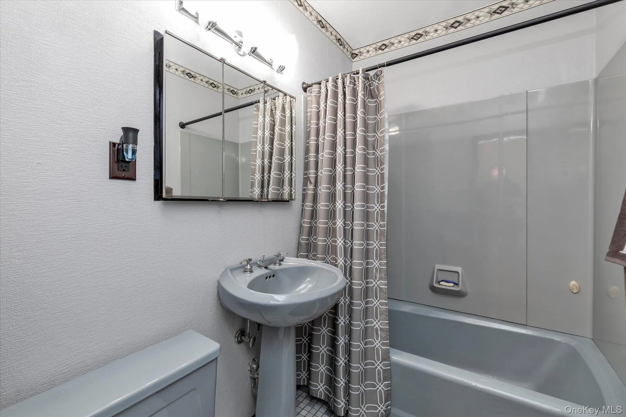 Bathroom featuring a pedestal sink, medicine cabinet, and a bathtub. Bathroom featuring a pedestal sink, medicine cabinet, and a bathtub.