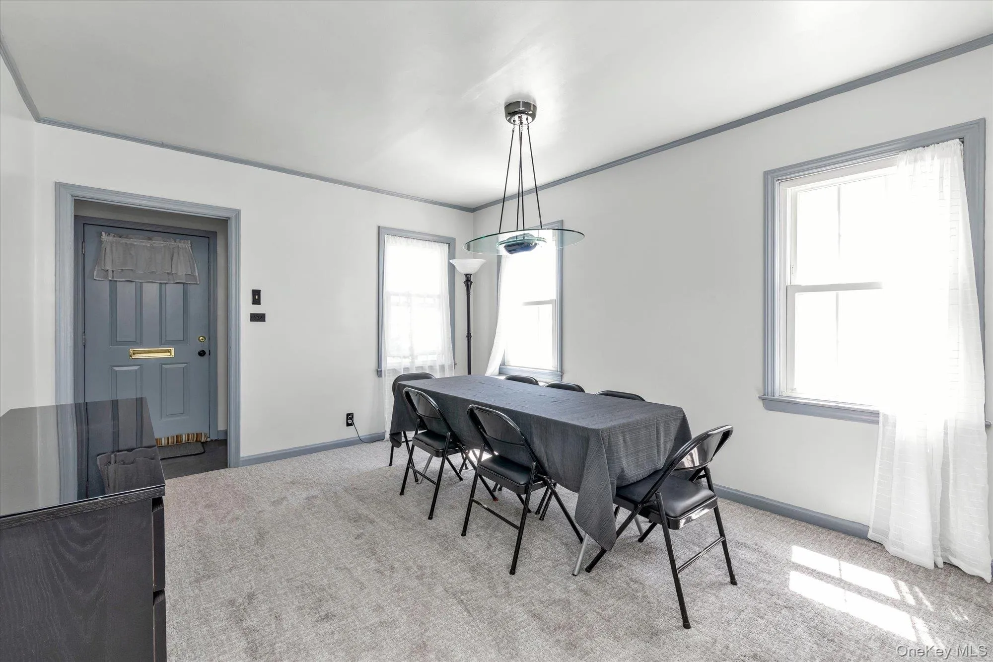 Carpeted dining or living room featuring a modern pendant light fixture and two double-hung windows. Carpeted dining or living room featuring a modern pendant light fixture and two double-hung windows.