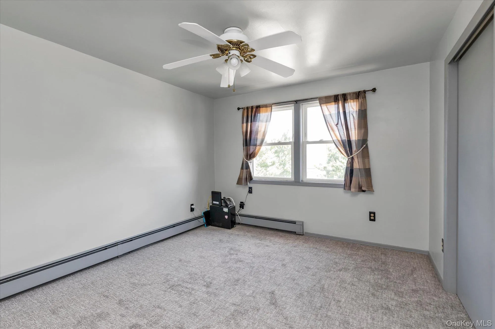 Carpeted and sunlit 3rd bedroom with ceiling fan and, baseboard heating. Carpeted and sunlit 3rd bedroom with ceiling fan and, baseboard heating.