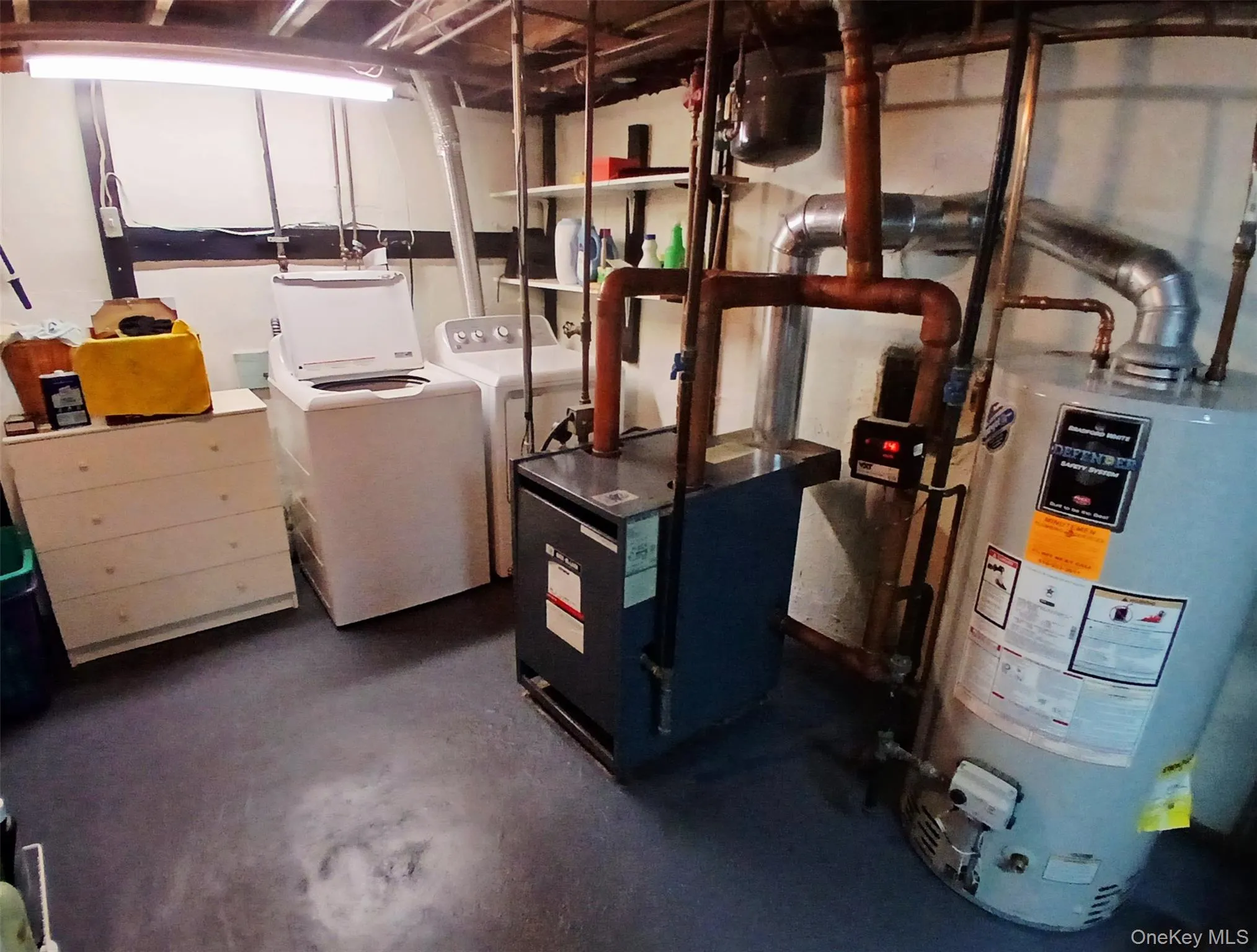 Mechanical room featuring a water heater, boiler system, and laundry area. Mechanical room featuring a water heater, boiler system, and laundry area.