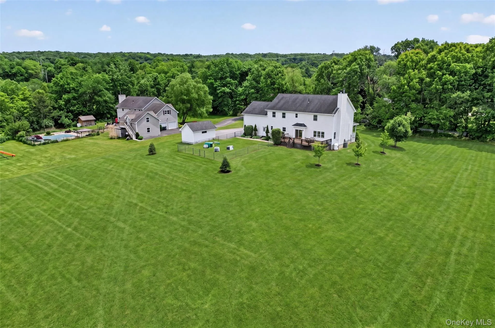 Spacious green lawn surrounding a two-story residence with mature trees bordering the property Spacious green lawn surrounding a two-story residence with mature trees bordering the property