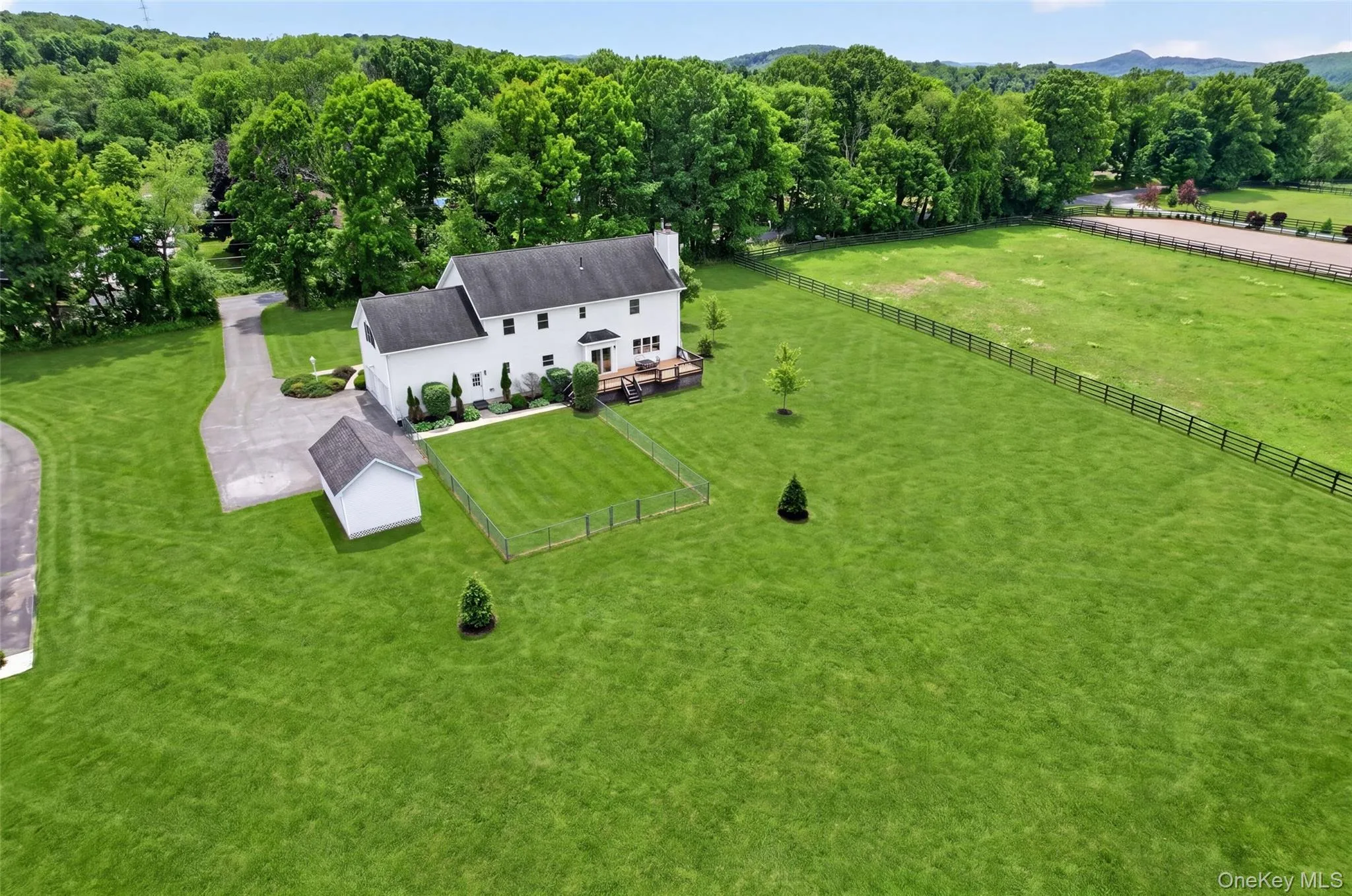 Expansive green lawn surrounds a white two-story residence with a dark roof Expansive green lawn surrounds a white two-story residence with a dark roof