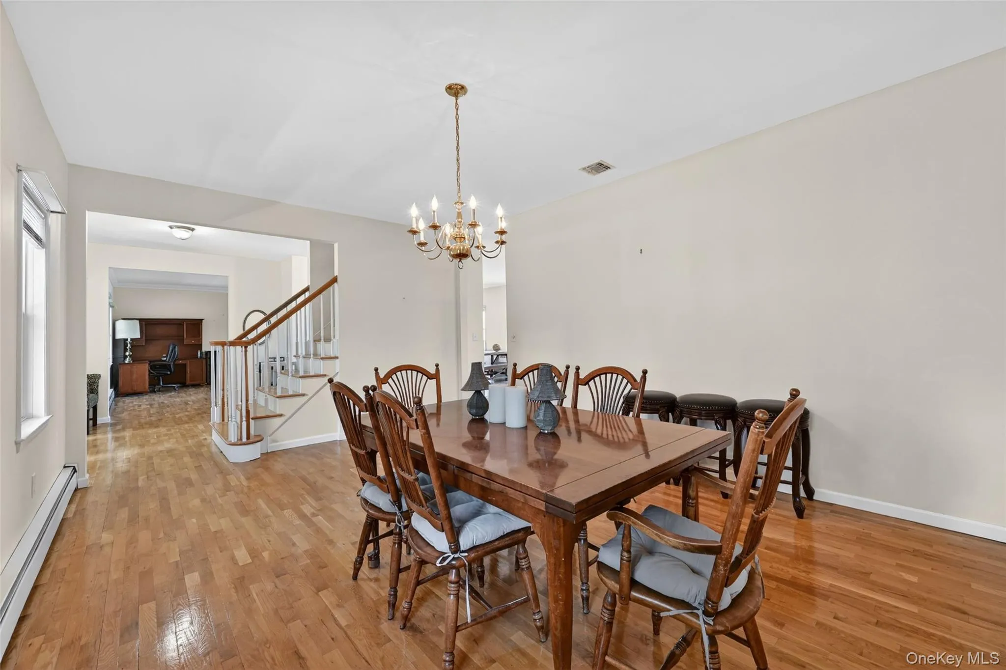 Dining area featuring wood-finish flooring, a brass chandelier, and light-toned wall paint Dining area featuring wood-finish flooring, a brass chandelier, and light-toned wall paint