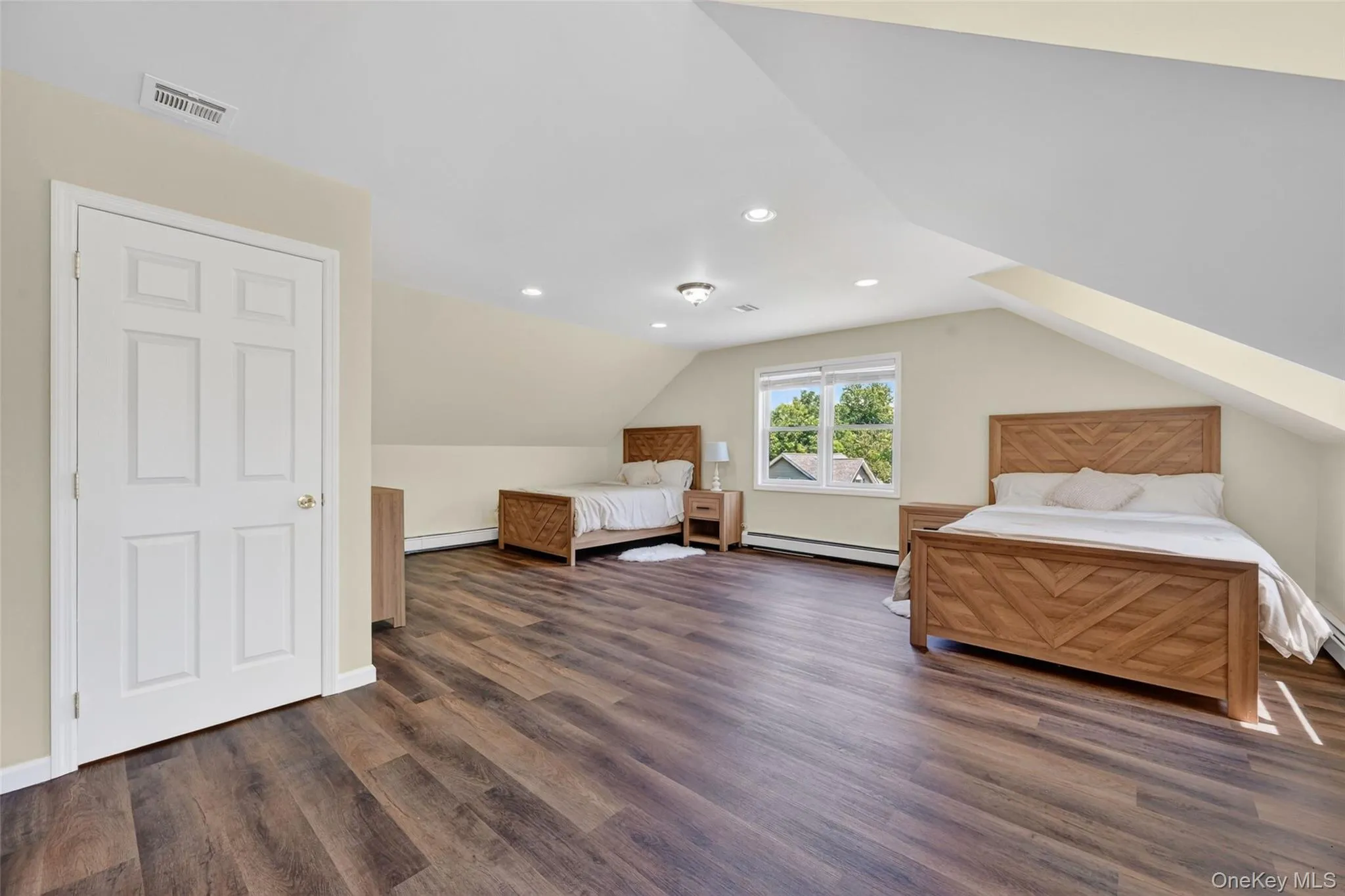 Spacious room featuring wood-finish flooring, recessed lighting, a multi-pane window, and light-toned walls Spacious room featuring wood-finish flooring, recessed lighting, a multi-pane window, and light-toned walls