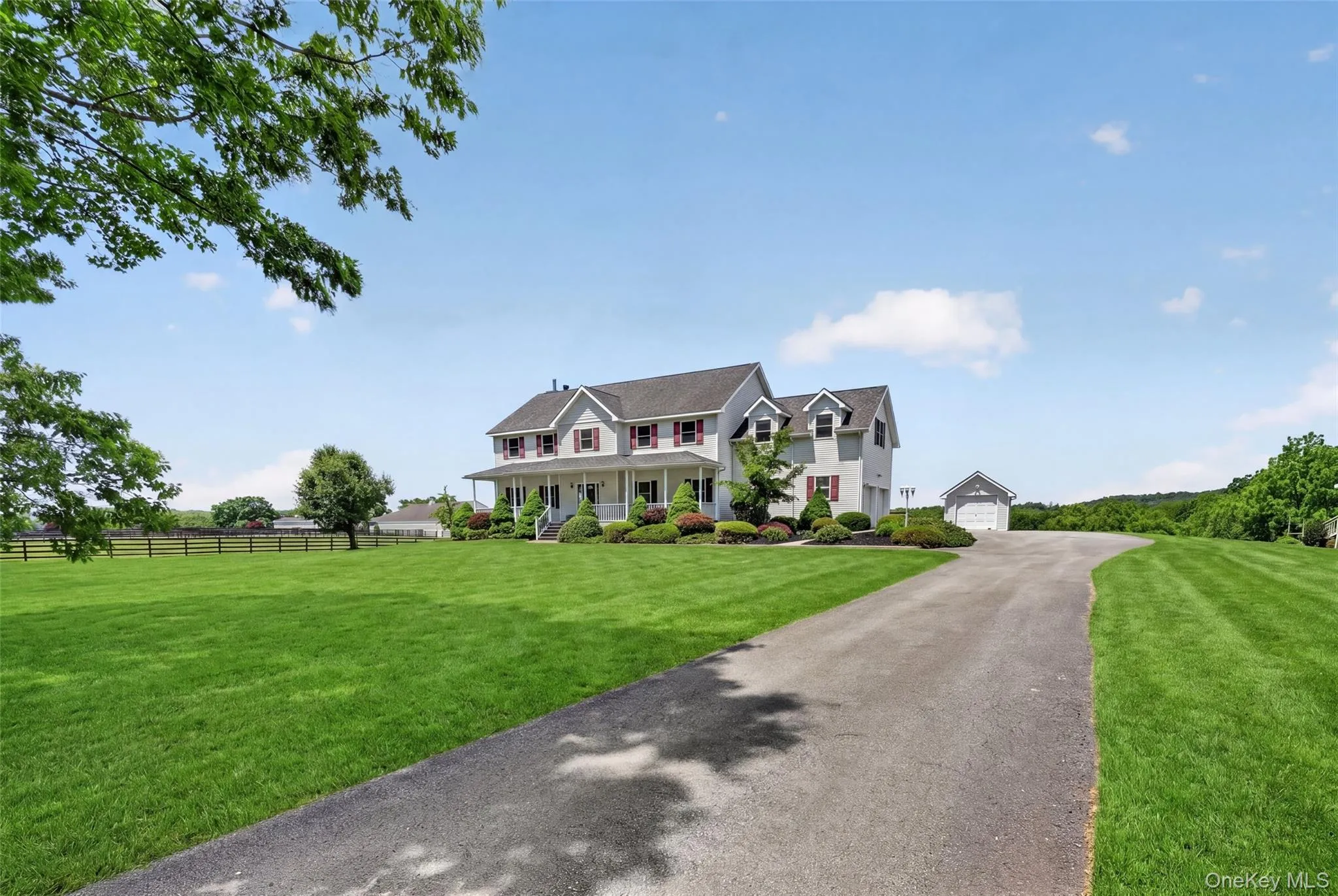 Expansive property featuring a spacious front lawn, paved driveway, and detached garage structure Expansive property featuring a spacious front lawn, paved driveway, and detached garage structure