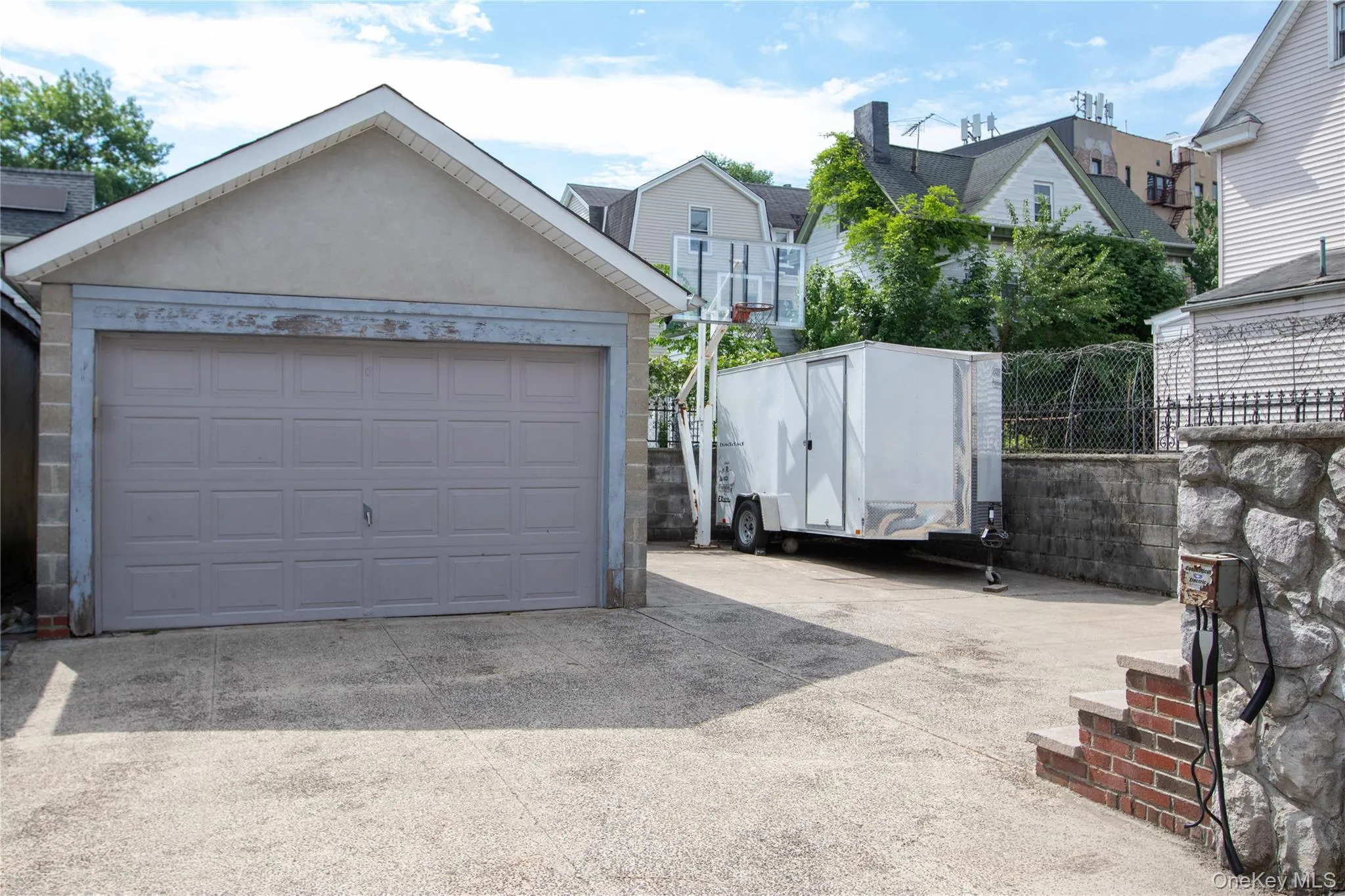 Detached garage with a paneled door, stucco finish, and an asphalt shingle roof. Electric Car Charging Station in Garage Detached garage with a paneled door, stucco finish, and an asphalt shingle roof. Electric Car Charging Station in Garage