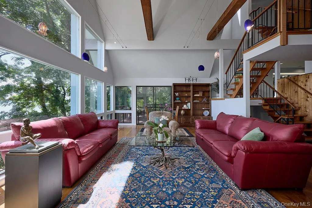 Living room featuring extensive window walls, exposed wood ceiling beams, and wood-finish flooring Living room featuring extensive window walls, exposed wood ceiling beams, and wood-finish flooring