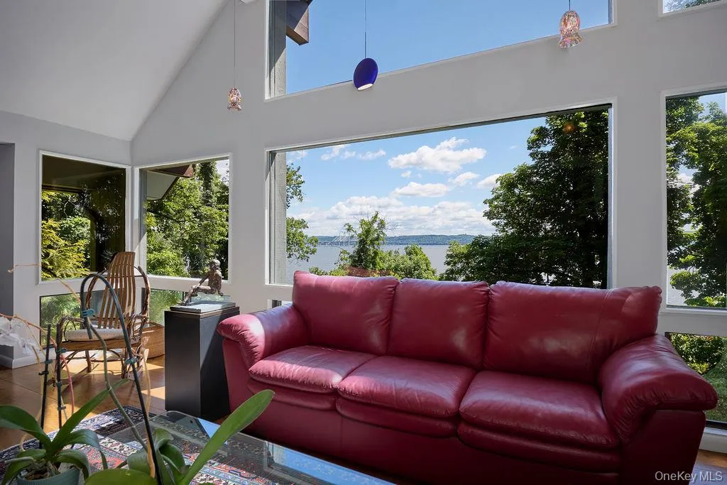 Interior space featuring vaulted ceilings, expansive windows, wood-finish flooring, and pendant lighting Interior space featuring vaulted ceilings, expansive windows, wood-finish flooring, and pendant lighting