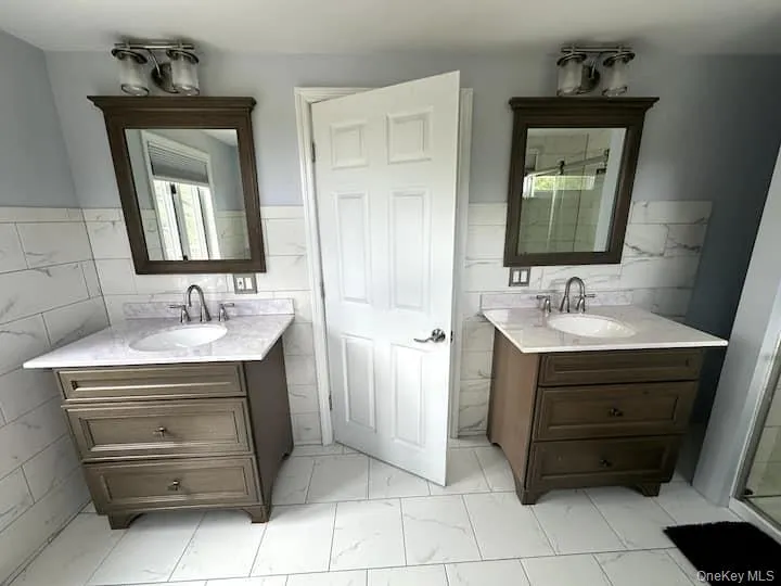 Dual vanity arrangement featuring dark wood-finish cabinetry, integrated sinks, and polished chrome fixtures Dual vanity arrangement featuring dark wood-finish cabinetry, integrated sinks, and polished chrome fixtures