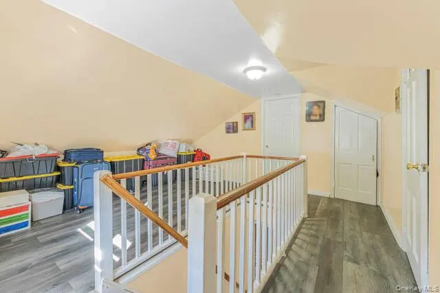 Upper-level landing featuring a white wood-finish railing with a natural wood-tone top rail, wood-finish flooring, and a Upper-level landing featuring a white wood-finish railing with a natural wood-tone top rail, wood-finish flooring, and a