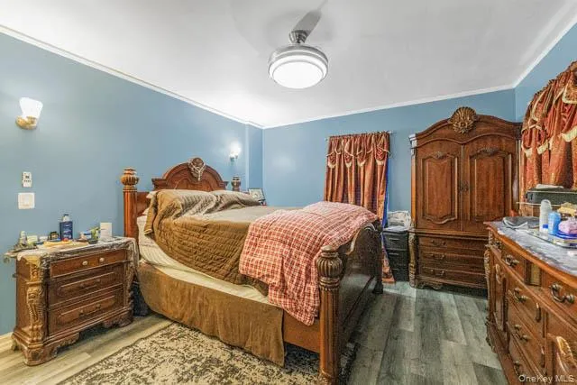 Spacious room featuring wood-finish flooring, a ceiling fan with integrated lighting, and crown molding Spacious room featuring wood-finish flooring, a ceiling fan with integrated lighting, and crown molding