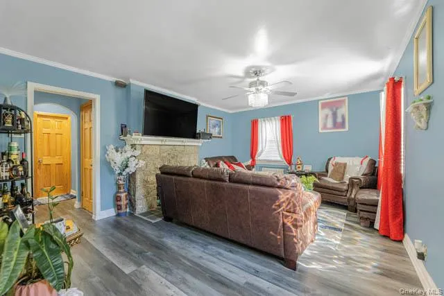 Living area featuring wood-finish flooring, light blue walls, and a stone-clad fireplace with a mantel Living area featuring wood-finish flooring, light blue walls, and a stone-clad fireplace with a mantel