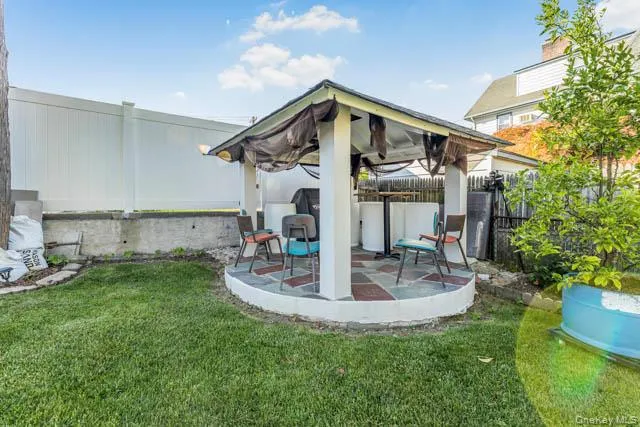 Backyard gazebo with a tiled floor, white support pillars, and surrounding lawn Backyard gazebo with a tiled floor, white support pillars, and surrounding lawn