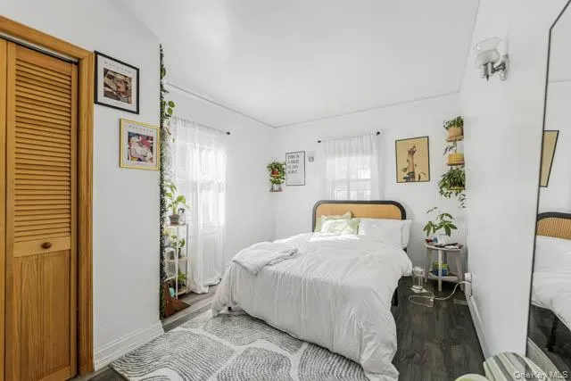 Bedroom featuring dark wood-finish flooring and white walls Bedroom featuring dark wood-finish flooring and white walls