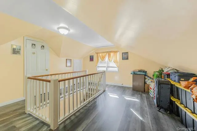 Upper-level landing featuring a white wood-finish railing with a natural wood-tone top rail, wood-finish flooring, and a window providing natural light Upper-level landing featuring a white wood-finish railing with a natural wood-tone top rail, wood-finish flooring, and a window providing natural light