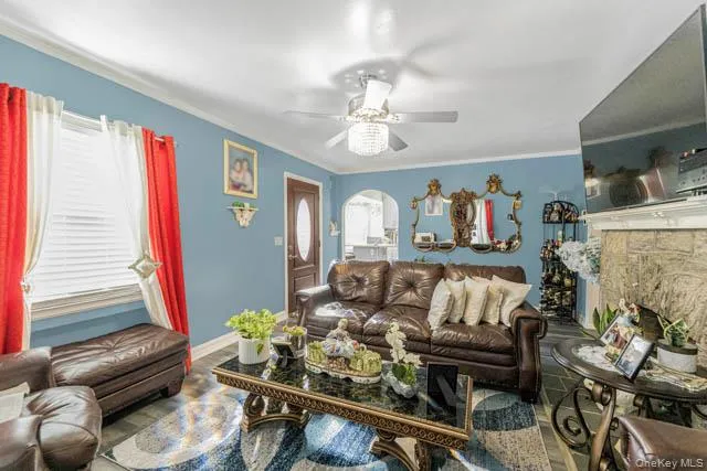 Living area featuring wood-finish flooring, a decorative ceiling fan, and crown molding Living area featuring wood-finish flooring, a decorative ceiling fan, and crown molding