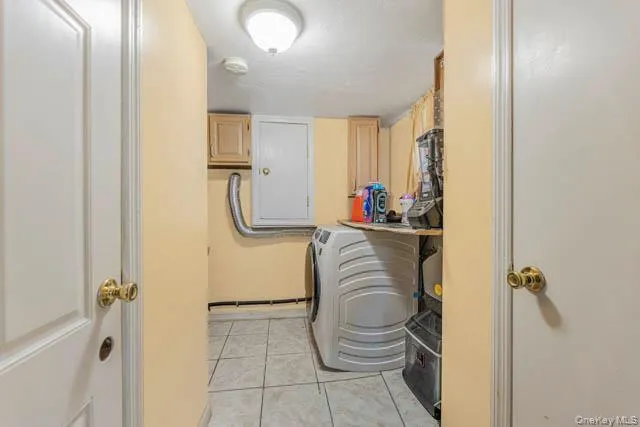 Dedicated utility area featuring a front-load washing machine, tile flooring, and wall-mounted cabinetry Dedicated utility area featuring a front-load washing machine, tile flooring, and wall-mounted cabinetry