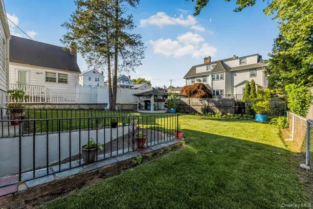 Expansive lawn with a black wrought iron fence and concrete retaining wall Expansive lawn with a black wrought iron fence and concrete retaining wall