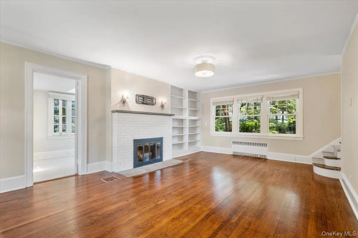 Living room with hardwood floors, a brick fireplace and view of the sunroom Living room with hardwood floors, a brick fireplace and view of the sunroom