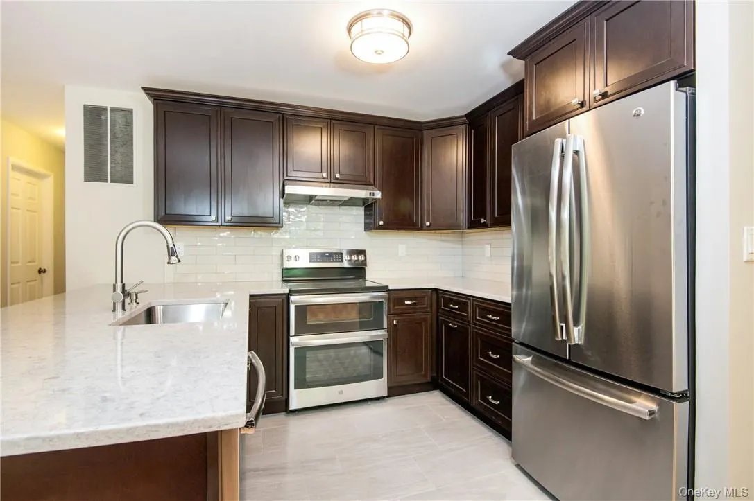 Renovated kitchen with brand-new appliances, granite countertops, dark wood cabinetry and subway tile backsplash. Renovated kitchen with brand-new appliances, granite countertops, dark wood cabinetry and subway tile backsplash.