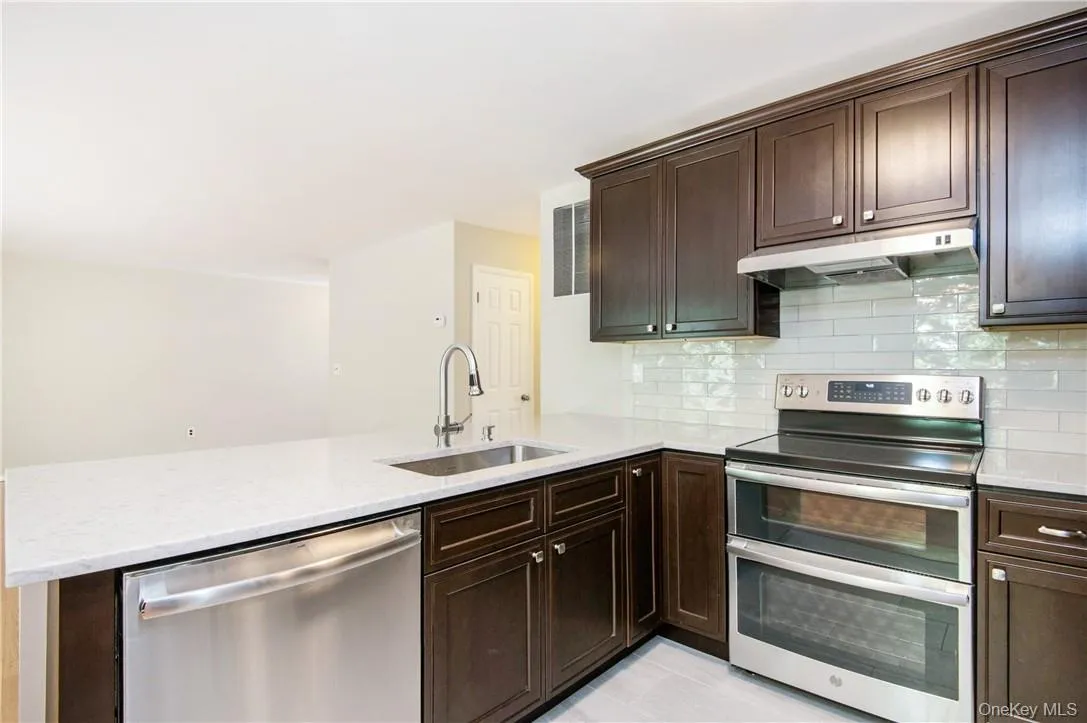 Renovated kitchen with brand-new appliances, granite countertops, dark wood cabinetry and subway tile backsplash. Renovated kitchen with brand-new appliances, granite countertops, dark wood cabinetry and subway tile backsplash.